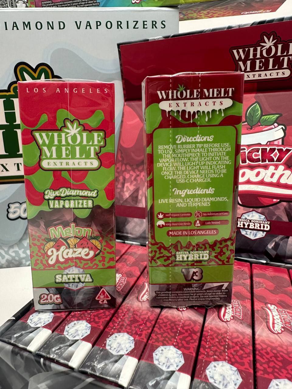 Boxes of Import placeholder for 37 vaping products are displayed. One box reads "Melon Haze" and features green and red cannabis imagery. The back of the box includes directions and ingredients, highlighting THC content and its sativa classification.