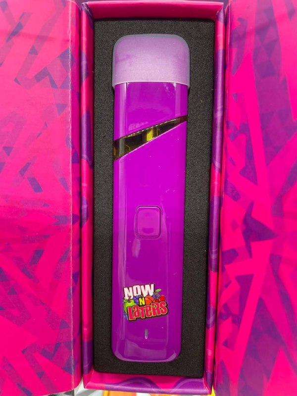 A close-up of a bright purple vape pen with a glossy finish, encased in foam inside a pink and purple box. The vape pen features a diagonal gold stripe, a central button, and a sticker that reads "Whole Melts Now and Laters.