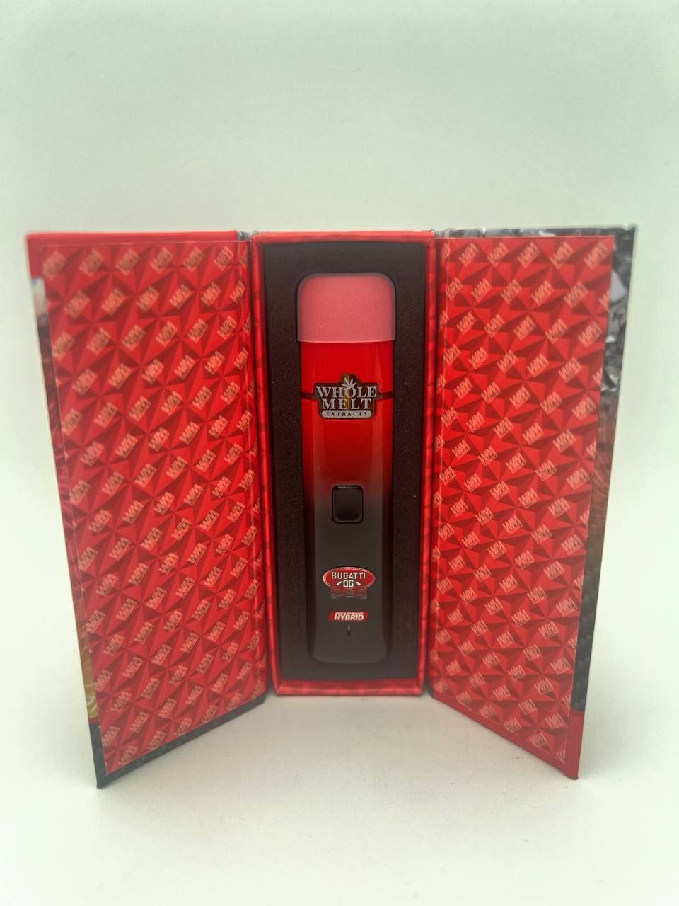 A red Import placeholder for 27 stands upright inside an open decorative red box with repetitive white logo pattern. The Import placeholder for 27 features the logo "WHOLE MELT EXTRACTS" and includes the text "HYBRID" and "0.8g." The interior of the box matches the exterior pattern.
