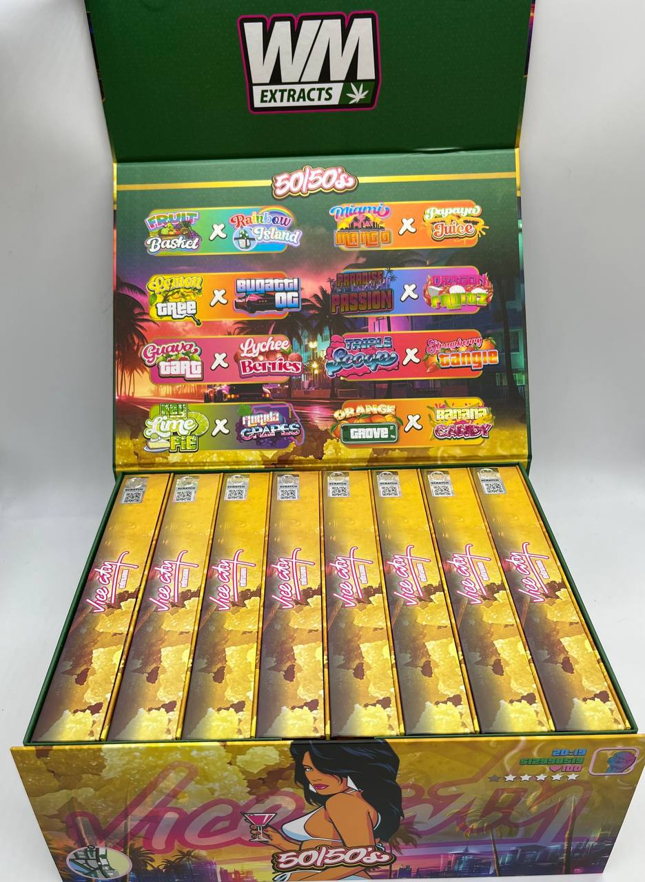 An open box of Whole Melt Vice City Edition vape cartridges by WM Extracts is displayed. The box showcases various flavors such as Forbidden Gushi, Lychee Passion, Sunset Gelato, and others. The colorful packaging is prominently labeled and decorated with vibrant graphics.