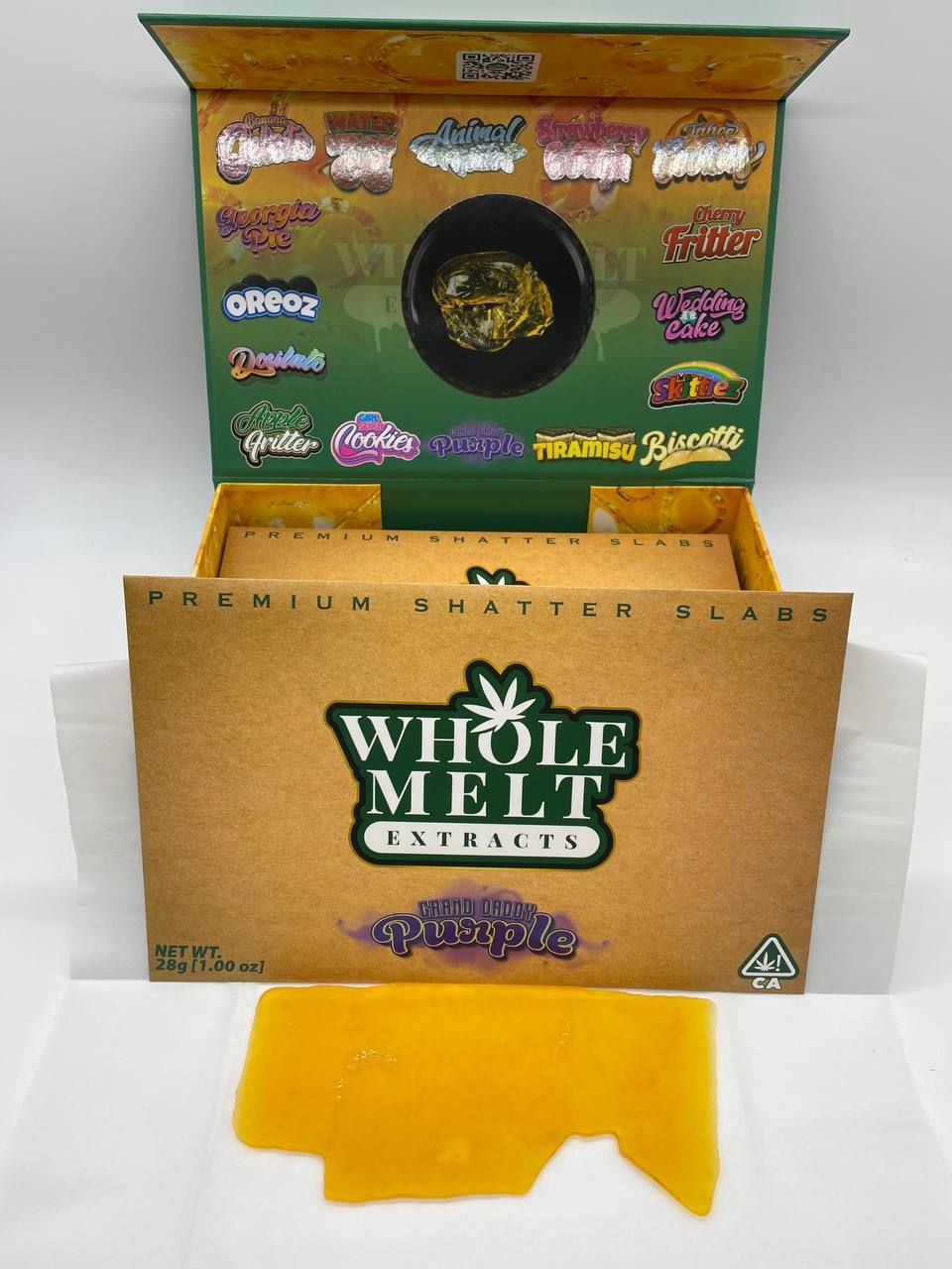 A box labeled "Import placeholder for 34" is open, displaying a golden shatter slab in front. The box features various strain names in colorful fonts on the inner lid, while the front of the box includes "Paris OG x Purple" with a cannabis leaf logo.
