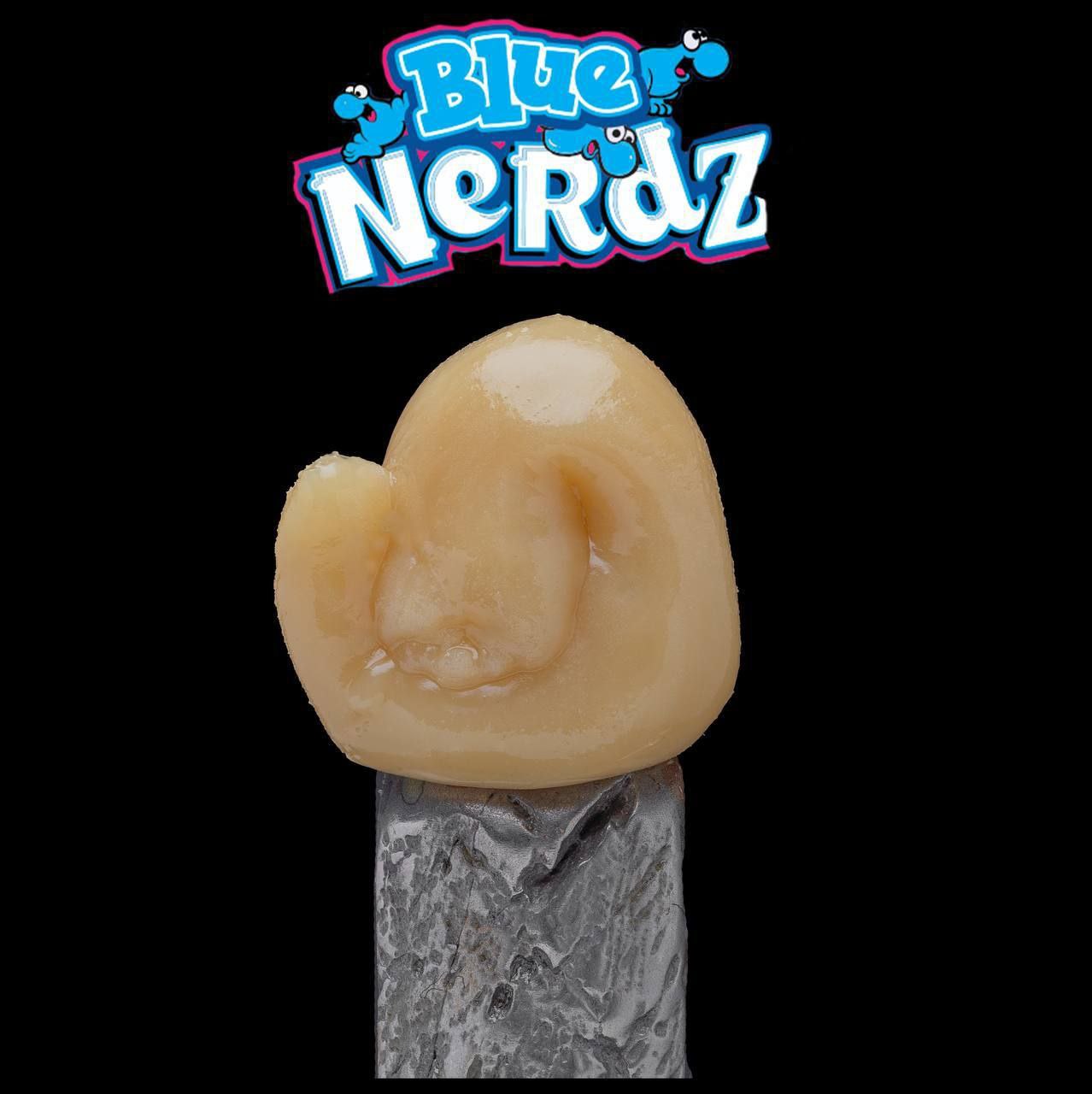 A close-up of a caramel-colored gummy candy shaped like an ear, held by a pair of metal tweezers. Above the candy, there is a logo reading "Import placeholder for 18" in blue and white text against a black background.